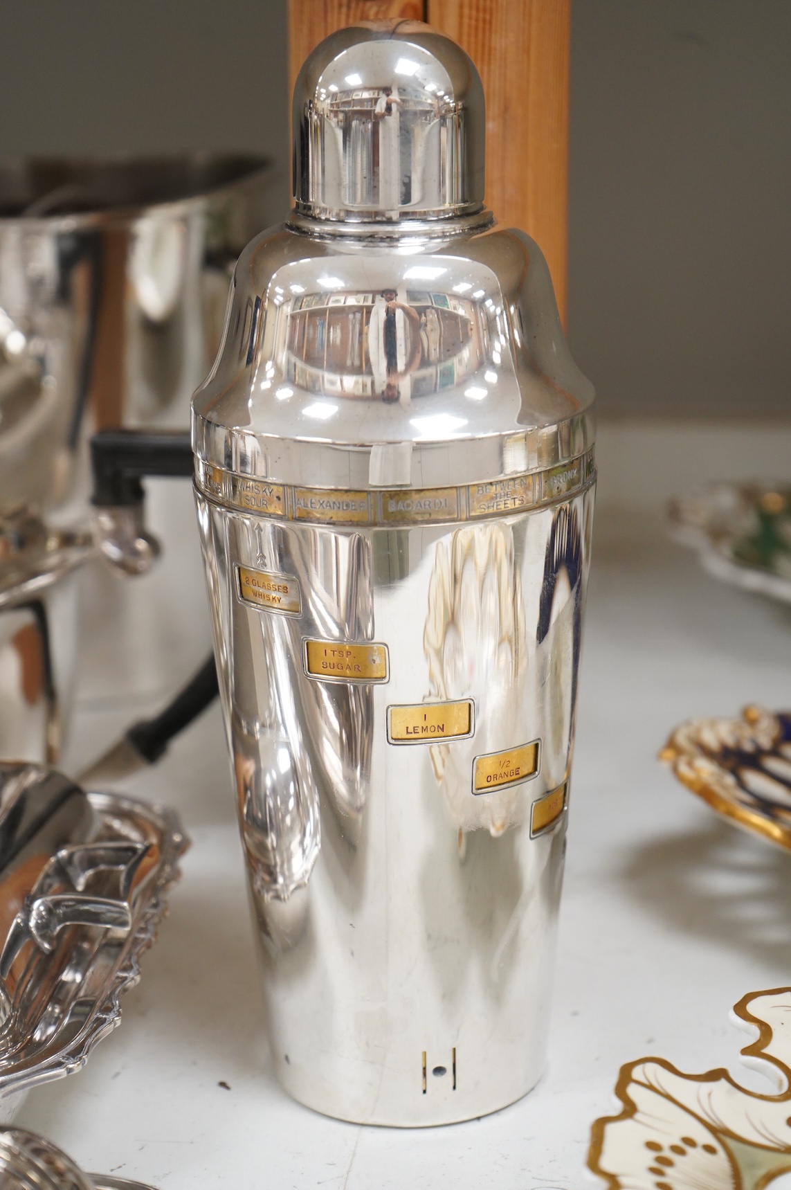 A collection of plated wares to include a vintage cocktail shaker with recipes, wine cooler and two plated entrée dishes including Art deco, largest 29cm wide